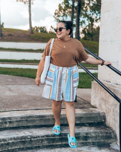 Fashionable woman in white top and sunglasses standing by yellow taxi on a bright day.